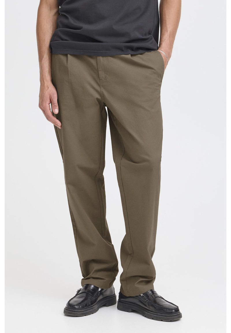 Khaki pants with a relaxed fit, flat front, and side pockets. Paired with black shoes, the fabric has a smooth texture and neutral tone.