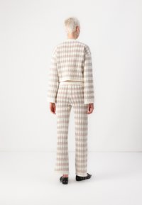 Ensemble en mailles assorti dans un motif à carreaux crème et beige ; pull court à manches longues et pantalon large ; tissu texturé avec des accents côtes.