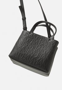 Borsa nera con design a testo in rilievo su tutta la superficie, caratterizzata da una forma strutturata, una texture liscia e una tracolla in pelle regolabile.