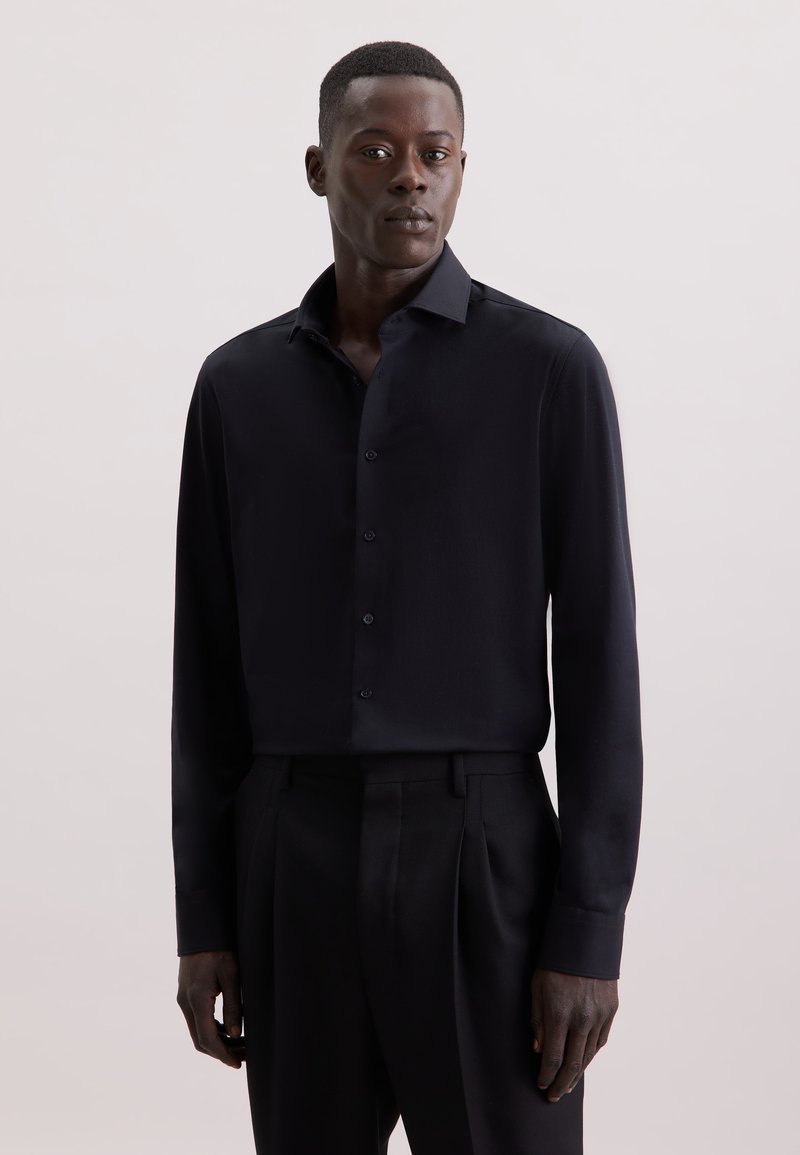 Camicia nera a maniche lunghe in tessuto liscio, chiusura con bottoni sul davanti, colletto classico, vestibilità su misura, mostrata con pantaloni abbinati e sfondo neutro.