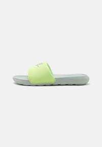 Lys grønn slidesandal med en teksturert syntetisk overdel og en grå såle, med en synlig logo på stroppen og et flatt design.