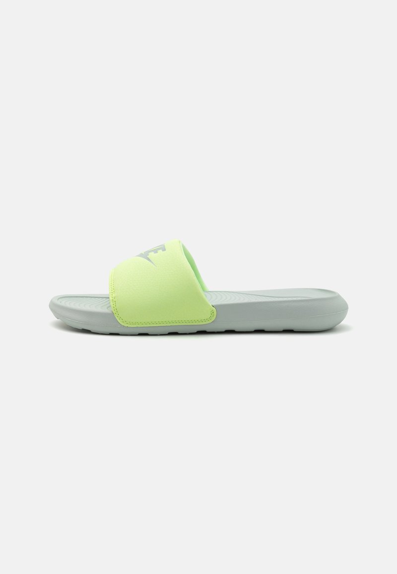 Lys grønn slidesandal med en teksturert syntetisk overdel og en grå såle, med en synlig logo på stroppen og et flatt design.