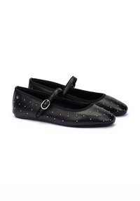 Bailarinas negras con punta redonda, adornadas con pequeños clavos plateados, presentan una correa de tipo Mary Jane y una parte superior de sintético liso.