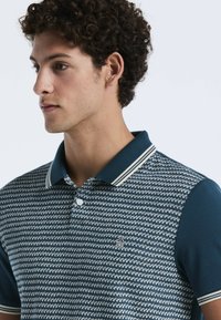 Polo shirt met een blauw-wit patroon, geribbelde kraag met witte strepen en een klein logo op de borst. Glad materiaal.