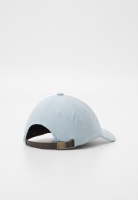 Casquette en velours côtelé bleu clair avec une visière courbée, attache ajustable marron à l'arrière et coutures contrastantes sur les œillets.