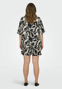 Doppelpack aus kurzärmeligem, locker sitzendem Oberteil und Shorts in einem schwarz-creamfarbenen abstrahierten Muster. Der Stoff wirkt leicht und hat eine strukturierte Oberfläche.