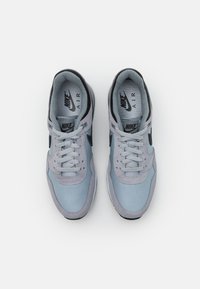 Zapatillas Nike Air en materiales azul claro y gris con acentos en negro. Cuenta con un collar acolchado, malla transpirable y cordones planos.