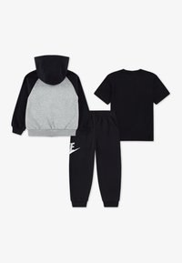 Sweat à capuche avec un corps gris et des manches noires, associé à un t-shirt noir et un pantalon arborant un logo blanc sur la jambe. Matériau en coton.
