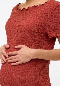 Haut rouge texturé avec un col à volants et des manches courtes, design ajusté, présentant un motif de tissu froissé.