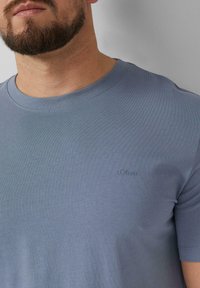 Lichtblauw T-shirt met korte mouwen van gladde katoenstof. Bevat een subtiel reliëf logo "s.Oliver" aan de linkerkant.