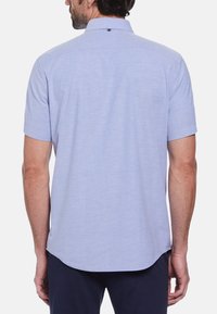 Korte mouwen, lichtblauw overhemd met knopen en kraag. Zachte stof, eenvoudig ontwerp en een gebogen zoom op de taille. Achterzijde heeft een klein lusje.