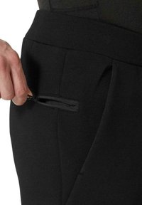 Pantalones negros con un bolsillo lateral funcional que cuenta con una cremallera segura, fabricados con una tela suave y elástica. La cintura es elegante y ajustada.