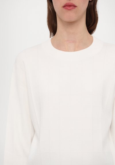 Biely pletený sveter s textúrovaným mriežkovým vzorom a okrúhlym výstrihom. Má dlhé rukávy a jemný, hladký povrch textílie.