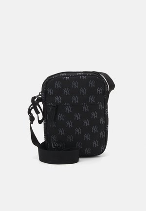 Black crossbody bag with a patterned NY logo. Features a zip closure, adjustable strap, and textured fabric. Compact rectangular shape.