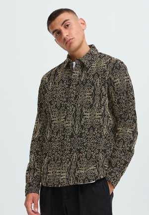 Black shirt featuring intricate gold floral and swirling patterns, with a collared neckline and long sleeves.
