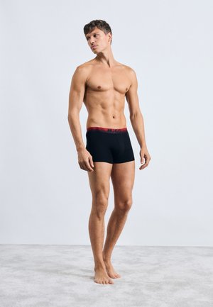 Boxer in cotone neri con un elastico rosso "HUGO", design aderente, tessuto morbido e senza motivi visibili o ulteriori accenti.