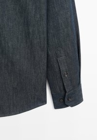 Dunkelblauses Denim-Hemd mit langen Ärmeln, das über einen knöpfbaren Bund, eine feine Textur und einen abgerundeten Saum verfügt. Die Knöpfe sind dunkel und rund.