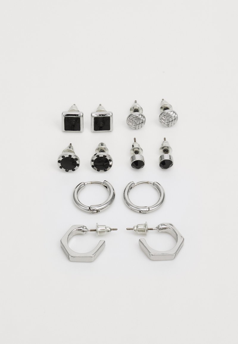 Conjunto de pendientes en tono plateado, que incluye dos pares de aros y seis pares de stud en diversas formas y texturas, incluyendo acentos en negro.