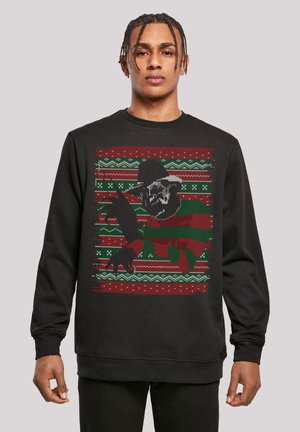 Sort sweatshirt med et grimt sweaterdesign, der har rød og grønne mønstre, der viser en karakter med en hat og kløer.