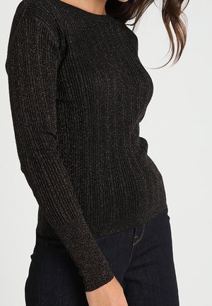 Schwarzer Langarm-Rippstrickpullover mit metallischen Fäden, figurbetonter Schnitt, runder Ausschnitt und strukturierter Oberfläche. Kombiniert mit dunklen Jeans.