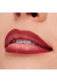 Matt dyp bær farge leppestift på fyldige lepper, som viser glatt tekstur og definerte kanter. Den naturlige leppefargen er synlig mellom nyansene.