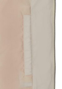 Polstret jakke fôr i lys beige og krem, med en sidelomme og synlige sømmer. Glatt tekstur med et rent design.