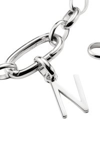 Collana d'argento con grandi anelli ovali, caratterizzata da un ciondolo a forma di lettera "N" sospeso. Finitura liscia e riflettente con forme degli anelli rotonde e piatte.