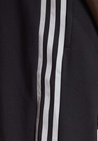 Pantalons noirs avec des rayures verticales blanches sur les côtés, en tissu mélangé coton doux, avec une coupe décontractée et des poches latérales.