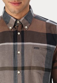 Καρό πουκάμισο με κουμπιά σε καφέ, γκρι και μαύρους τόνους. Διαθέτει τσέπη στο στήθος και διακοσμητικά κουμπιά από πέρλα. Ύφασμα από βαμβάκι με απαλό υφή.