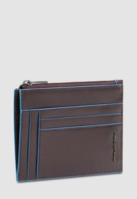 Bruine leren portemonnee met blauwe stiksels, voorzien van meerdere kaartsleuven en een ritscompartiment voor munten. Compact en strak ontwerp.