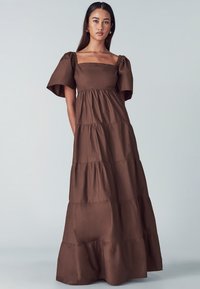 Brown tiered maxi dress with a square neckline and puff sleeves, made of soft fabric, featuring a relaxed silhouette and subtle texture.