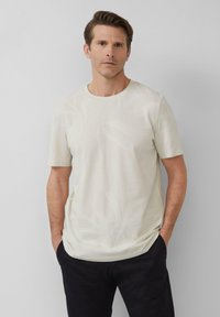 Lichtbeige t-shirt met korte mouwen, voorzien van een subtiel loofmotief. Gemaakt van een zachte stof, ontworpen met een ronde halslijn en een ontspannen pasvorm.