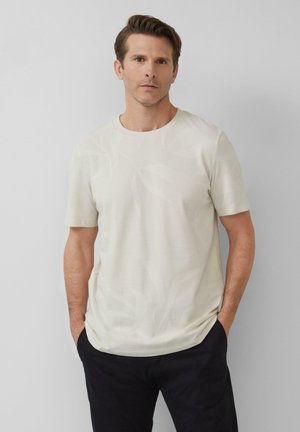 Lichtbeige t-shirt met korte mouwen, voorzien van een subtiel loofmotief. Gemaakt van een zachte stof, ontworpen met een ronde halslijn en een ontspannen pasvorm.