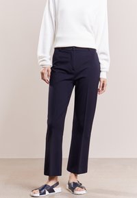 Navy skräddarsydda byxor med rak passform, med en slät tygtextur och en framknäppning. I kombination med en vit ribbad tröja.