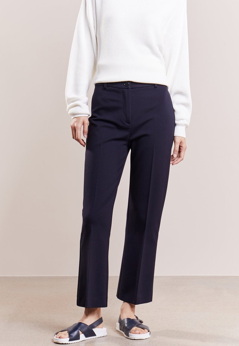 Navy skräddarsydda byxor med rak passform, med en slät tygtextur och en framknäppning. I kombination med en vit ribbad tröja.