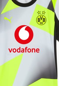 Camisa de fútbol gris con acentos en amarillo neón y detalles en negro. Presenta el logo de Puma, la marca Vodafone y el emblema del BVB 09 con dos estrellas.