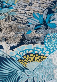 Floral fabric featuring intricate blue and yellow patterns on a navy background. Textured finish with leaves and flowers in varying shades.
