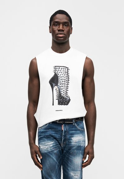 Λευκό αμάνικο μπλουζάκι με γραφικό σχέδιο ενός ψηλοτάκουνου παπουτσιού με καρφιά, συνδυασμένο με σκισμένο μπλε τζιν και μαύρη ζώνη.