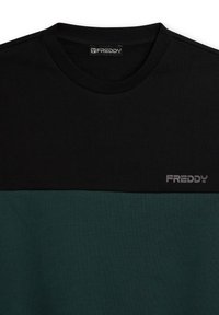 Camiseta de manga corta en negro y verde oscuro con cuello redondo, con un logo plateado "FREDDY" en el frente. Textura de tela suave.