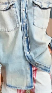 Ανοιχτό μπλε τζιν πουκάμισο με κουμπιά και δύο τσέπες στο στήθος, φορεμένο πάνω από λευκές σορτς με κατακόρυφες κόκκινες ρίγες.