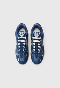 Par tenisica New Balance 1000 u tamnoplavoj boji s bijelim vezicama, viđeno odozgo na jednostavnoj bijeloj pozadini.