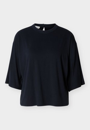 Zwarte oversized kortärmelige blouse met ronde halslijn en knoopsluiting aan de achterkant, afgebeeld op een witte achtergrond.
