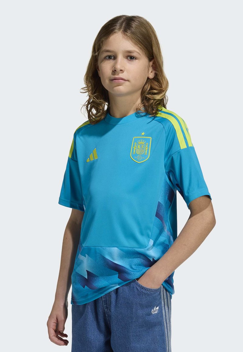 Ljusblå sporttröja i mjukt tyg. Har Spaniens riksvapen och neongula accenter på ärmarna. Abstrakt mönster nederst.