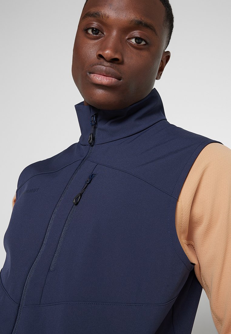 Granatowa bezrękawnik z wysokim kołnierzem, zapinany na zamek, z dwoma kieszeniami. Wykonany z trwałej, teksturowanej tkaniny.