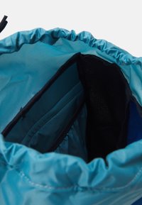 Bolsa de cordón en tela verde azulado con una abertura fruncida. Presenta un interior forrado con un bolsillo oscuro y un forro azul en contraste.