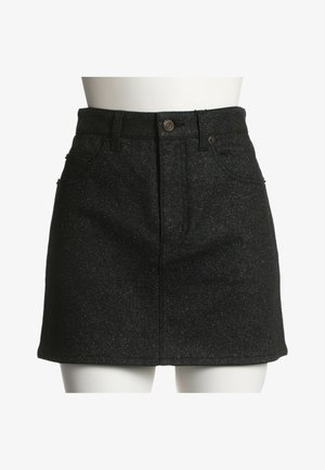 Mini-jupe en denim noir avec bouton sur le devant, fermeture éclair, passants pour ceinture et poches avant sur un mannequin blanc au niveau de la taille et des hanches.