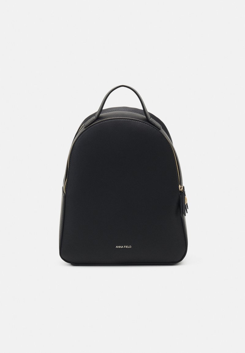 Sac à dos en cuir noir avec poignée supérieure, fermeture éclair dorée et petit logo blanc "Anna Field" à l'avant.