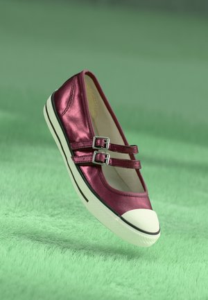 Burgundy metallic flat shoe with two buckle straps, white toe cap, and black sole accents, displayed against a soft green background.