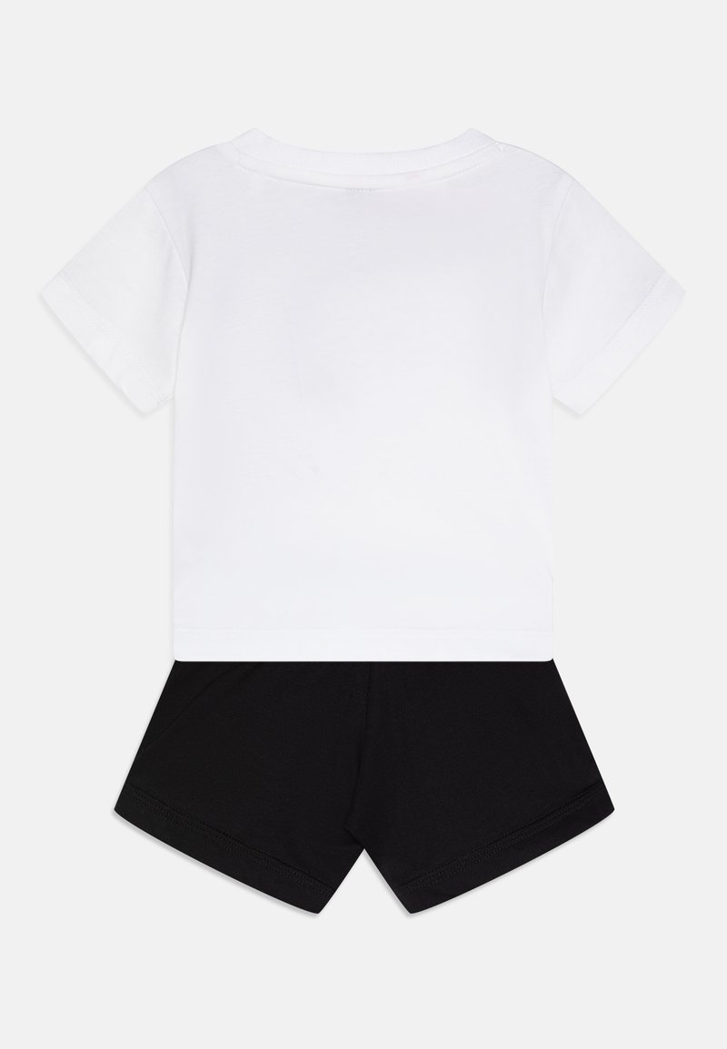 T-shirt blanc à manches courtes associé à un short noir. Le T-shirt présente une encolure ras du cou ; le short est lisse avec une taille élastique.