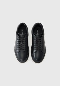 Zwarte leren sneakers met een gladde textuur, ronde neus en donkere veters. Voorzien van een minimalistisch ontwerp en subtiele branding op de binnenzool.